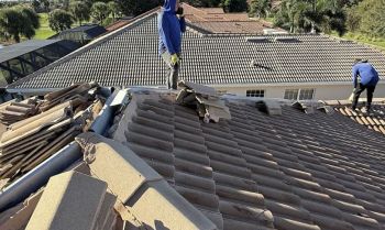 Roofing contractors repairing a tile roof on a residential home rooftop