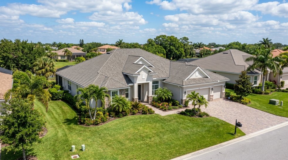 Large suburban home with gray shingle roof, driveway, and landscaped yard in a residential neighborhood